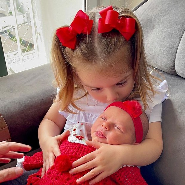 Liz, de 2 anos, com a irmãzinha recém-nascida, Ivy, no colo (Foto: Reprodução/Instagram)