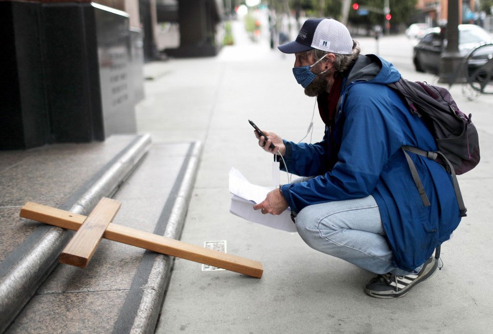 Ativista católico transmite pelo smartphone via crucis em Los Angeles, na Califórnia, na sexta-feira (10) — Foto:  Mario Tama / Getty Images via AFP