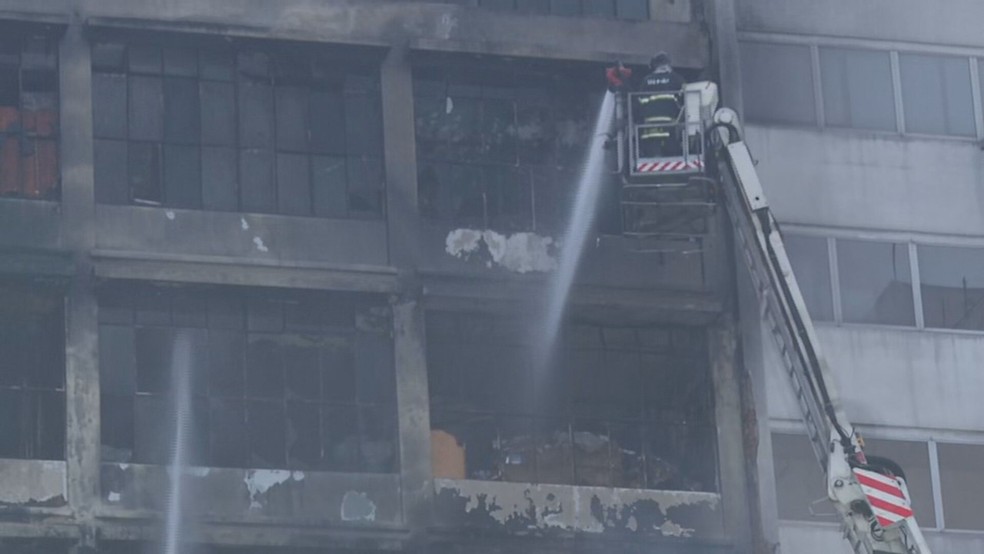 Bombeiros deixaram o prédio de 10 andares e fazem combate ao fogo do lado de fora, com mangueiras — Foto: Reprodução/TV Globo