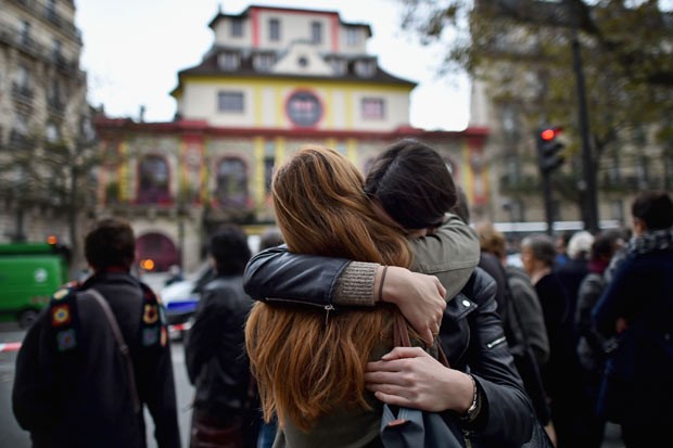 Duas mulheres se abraçam em frente à casa de shows Bataclan, onde 89 pessoas que assistiam a um show foram mortas (Foto: Getty Images)