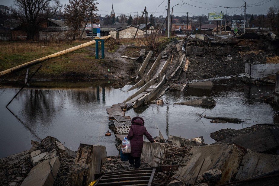 Mulher cruza ponte em meio a destroços na região de Bakhmut, Leste da Ucrânia