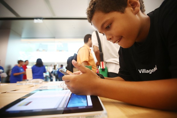 RIO DE JANEIRO, BRAZIL - FEBRUARY 15:  A boy plays with an iPhone in Brazil's first Apple retail store minutes after it opened to the public for the first time in the Village Mall shopping center on February 15, 2014 in Rio de Janeiro, Brazil. The store i (Foto: Getty Images)
