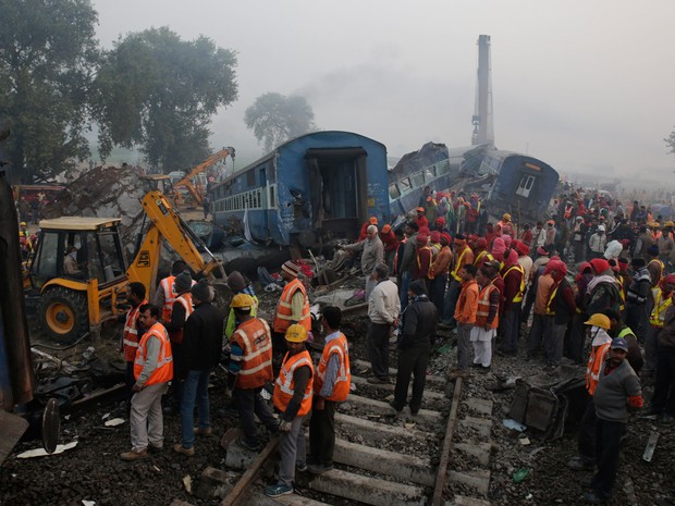 Equipes de resgate trabalham no local depois que 14 vagões de um trem noturno de passageiros descarrilaram perto da vila de Pukhrayan no distrito de Kanpur Dehat, na India. Mais de 100 pessoas morreram no acidente (Foto: Rajesh Kumar Singh/AP)