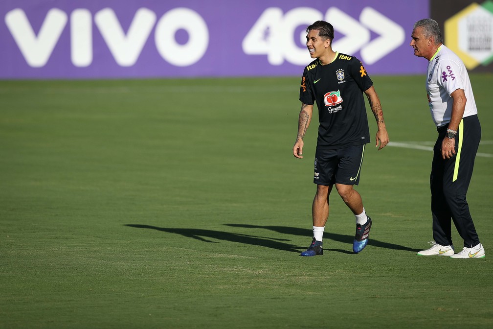 Sorridente, Firmino ouve as instruções de Tite num treino recente da seleção brasileira — Foto: Pedro Martins / MoWA Press