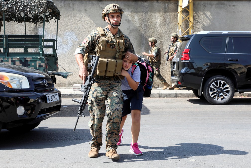 14 de outubro - Um soldado do exército ajuda uma estudante a chegar até seus pais depois que um tiroteio estourou em Beirute, no Líbano   — Foto: Mohamed Azakir/Reuters
