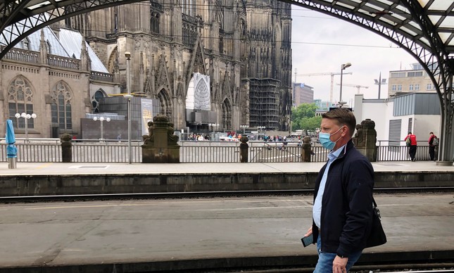 A passenger wearing a protective mask walks on a platform near a famous gothic cathedral in Cologne as Reuters journalist Gabriela Baczynska travels 1,300 kilometres across Europe from Brussels to her hometown Warsaw during the coronavirus disease (COVID-19) outbreak, in Cologne, Germany, June 10, 2020. Picture taken June 10, 2020. 