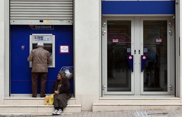 Homem saca dinheiro em caixa automático de Atenas, enquanto os bancos permanecem fechados por decisão do governo (Foto: Getty Images)