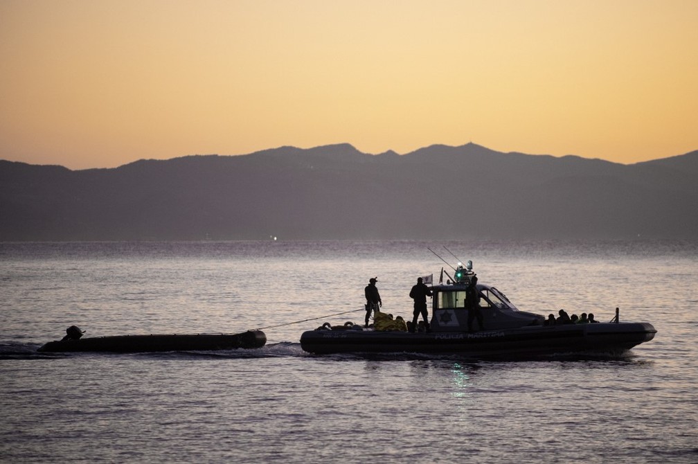 Patrulheiros rebocam um bote de refugiados no mar Egeu, perto da ilha grega de Lesbos, no domingo (29) — Foto: Angelos Tzortzinis/AFP