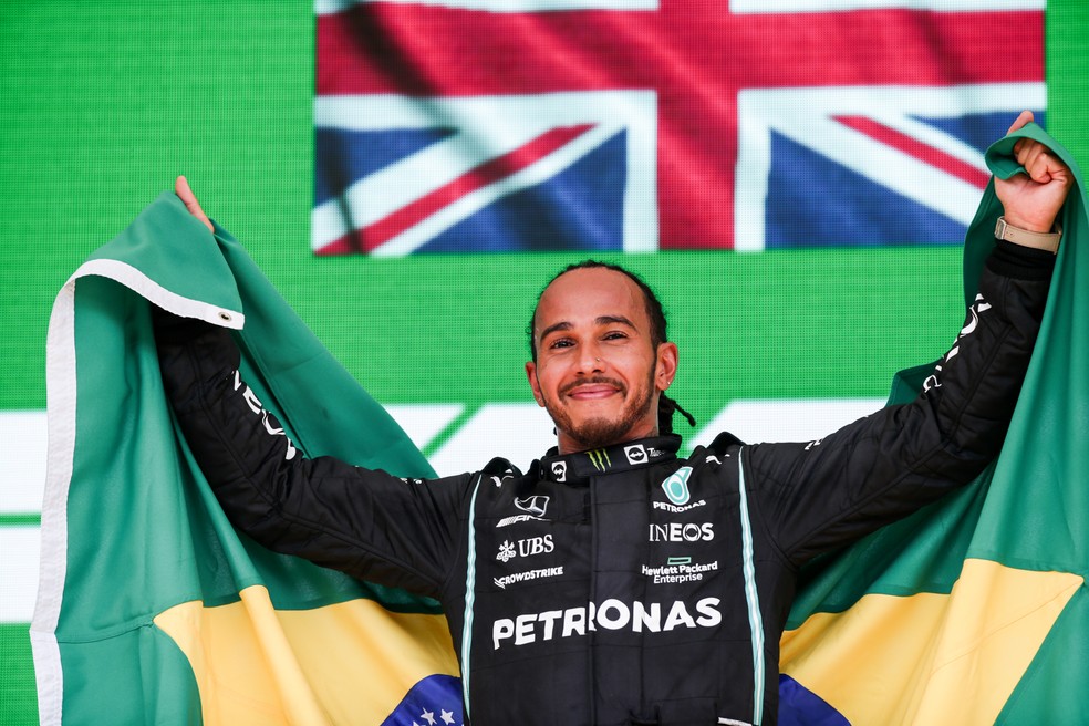 Lewis Hamilton comemora a vitória no GP de São Paulo de 2021 com a bandeira do Brasil no pódio — Foto: Peter Fox/Getty Images