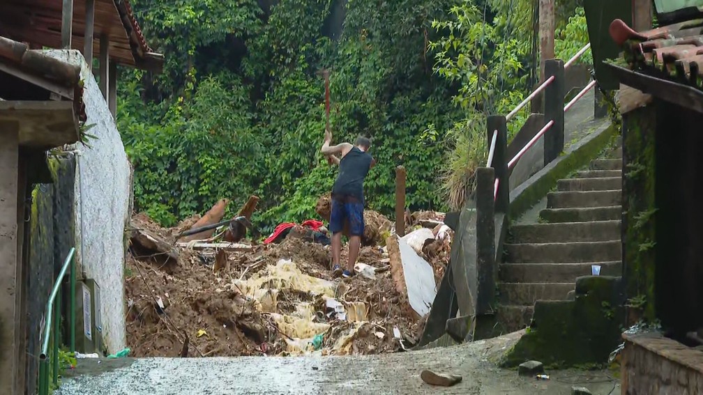 Homem faz busca em escombros no Morro da Oficina, em Petrópolis — Foto: Reprodução/ TV Globo