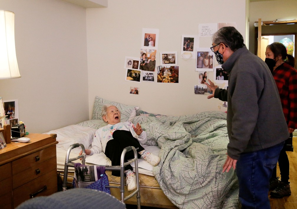 30 de março - Yoshia Uomoto, 98 anos, reage quando seu filho Mark Uomoto e a sobrinha Gail Yamada a surpreendem com sua primeira visita pessoal em um ano, depois que as restrições do covid-19 são suspensas em Nikkei Manor, uma residência assistida que atende principalmente idosos nipo-americanos, em Seattle, Washington, EUA — Foto: Lindsey Wasson/Reuters