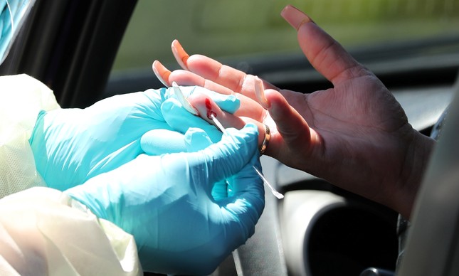 Profissional de saúde realiza teste rápido em motorista dentro de centro de testagem na cidade de Los Angeles, Califórnia, nos Estados Unidos