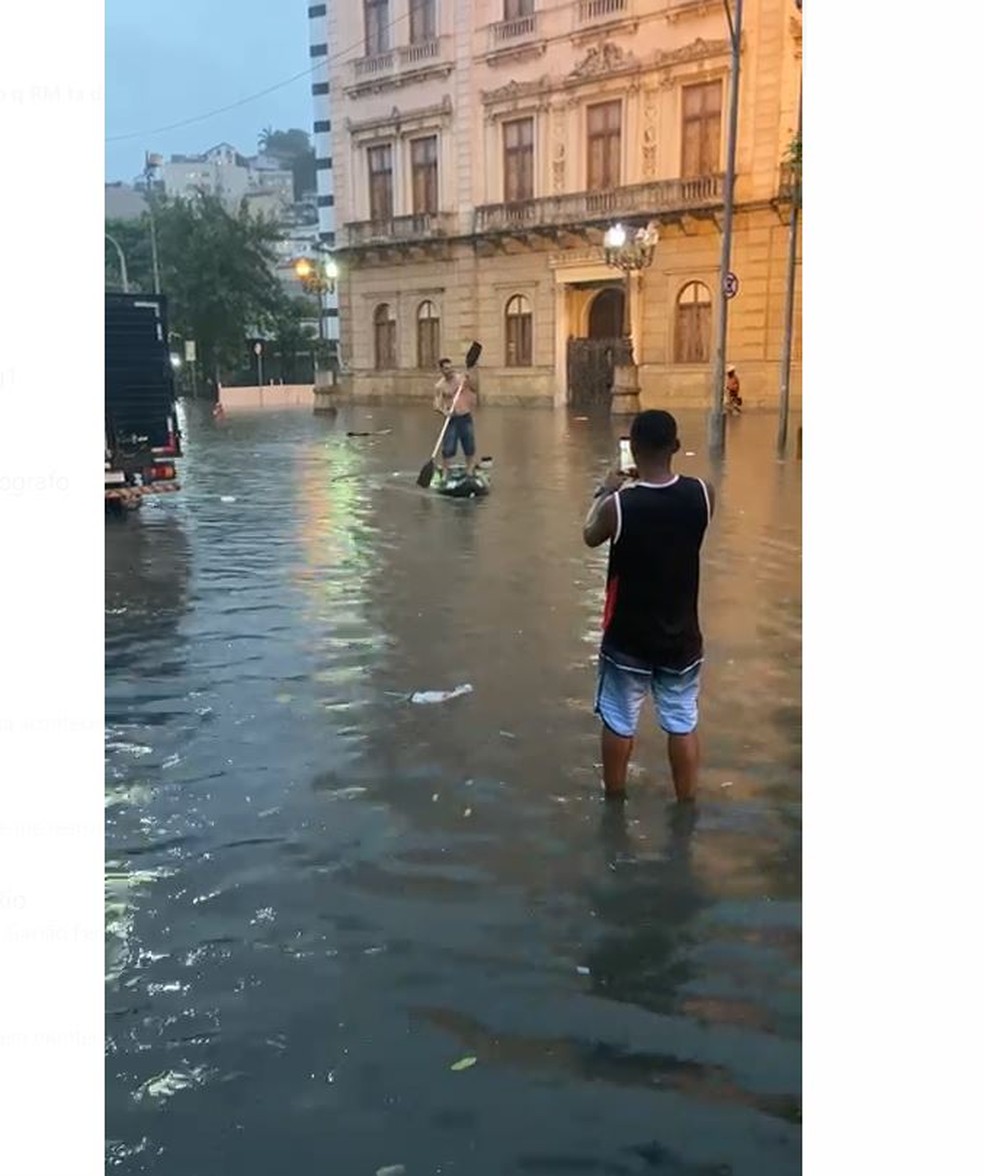 Homem anda da stand-up paddle no Catete com a rua alagada — Foto: Reprodução