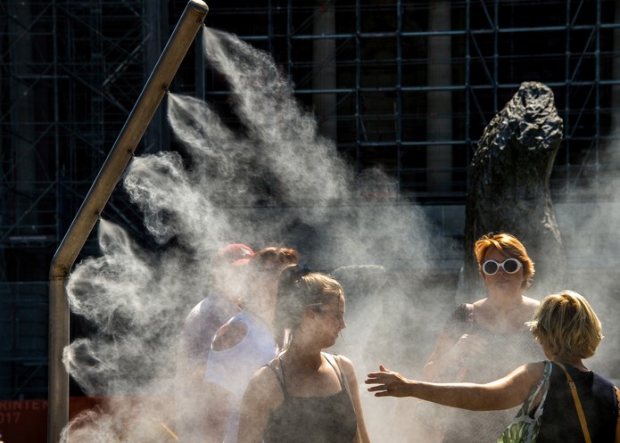 Mulheres se refrescam com borrifador de Ã¡gua pÃºblico em Lille, na FranÃ§a, durante onda de calor na Europa (Foto: Philippe Huguen/AFP)
