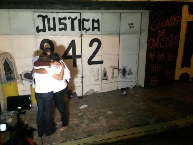 Familiares de vítimas se abraçam em frente à antiga porta de entrada da boate Kiss (Foto: Daniel Favero/G1)