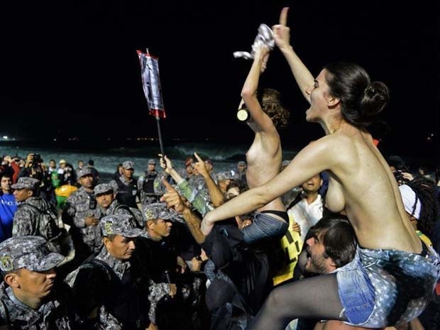 Manifestantes subiram nos ombros de colegas e, com os seios à mostra, provocaram fiéis que acompanhavam shows da Jornada Mundial da Juventude, em Copacabana (Foto: Tasso Marcelo/ AFP Photo)