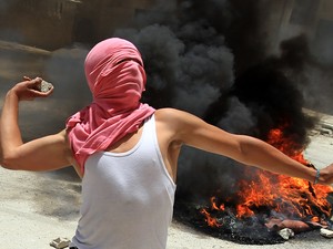 jovem palestino atira uma pedra em direção a soldados israelenses durante confrontos em Kafr Aqab, após uma incursão do Exército israelense na cidade (Foto: Abbas Momani/AFP)