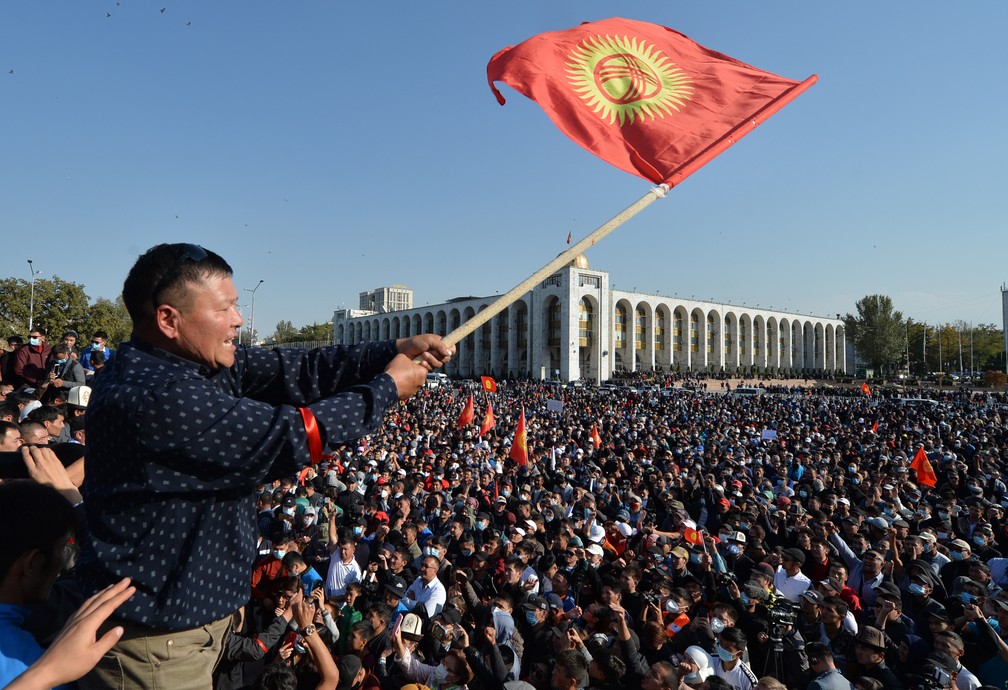 Manifestante ergue bandeira do Quirguistão diante de multidão que protesta em Bishkek em 5 de outubro — Foto: Vyacheslav Oseledko/AFP