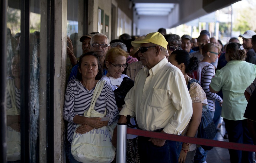 Clientes fazem fila do lado de fora de agência bancária em Maracaibo, na Venezuela, para obter notas da nova moeda (Foto: AP Photo/Fernando Llano)