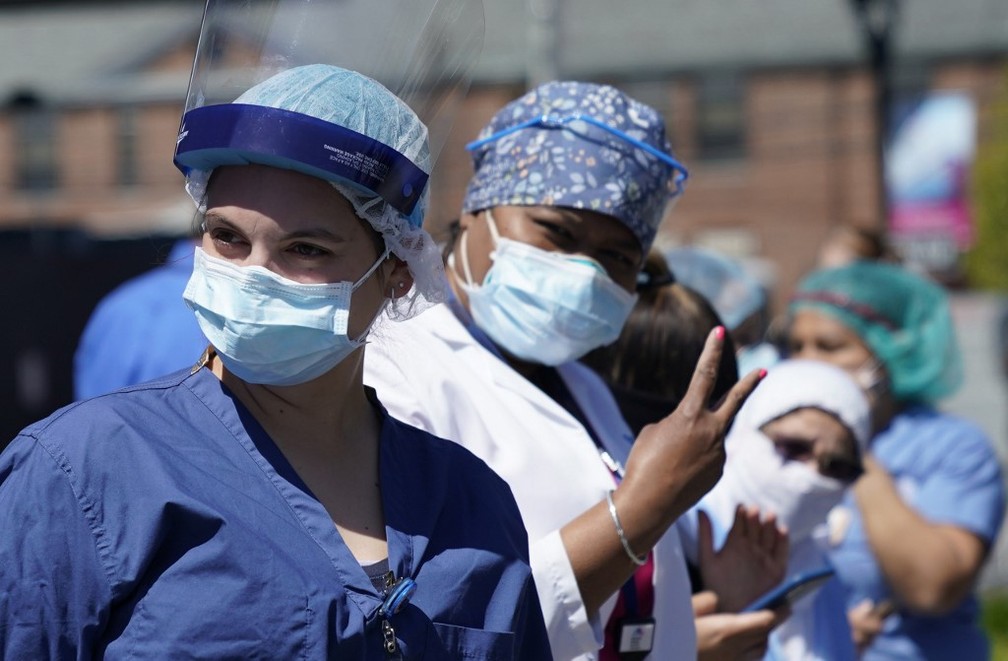 13 de maio: funcionários da linha de frente do combate ao coronavírus de um hospital em Oceanside, Nova York, observam parada de veículos feita em homenagem aos profissionais de saúde. — Foto: Timothy A. Clary/AFP