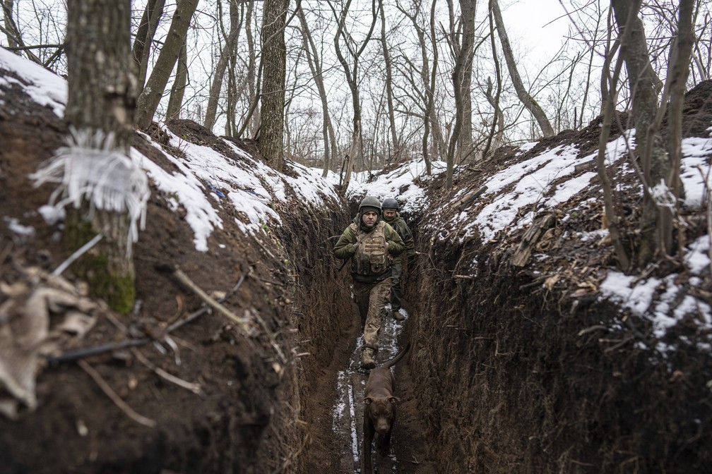 Dois militares ucranianos e um cachorro caminham ao longo de uma trincheira na linha de frente perto de Zolote, na Ucrânia, em 7 de fevereiro de 2022 — Foto: Evgeniy Maloletka/AP