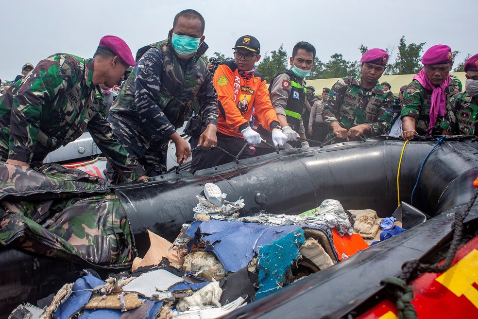 Soldados carregam destroços de avião que caiu na Indonésia, nesta terça-feira (30)  — Foto: Antara Foto/Ibnu Chazar via REUTERS 