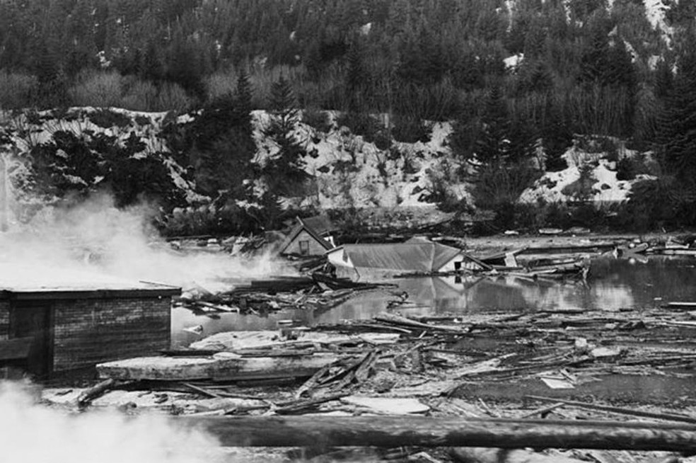 Fumaça de restos de tanques de óleo entre ruínas de casas após terremoto e maremoto no Alaska — Foto: Getty Images via BBC