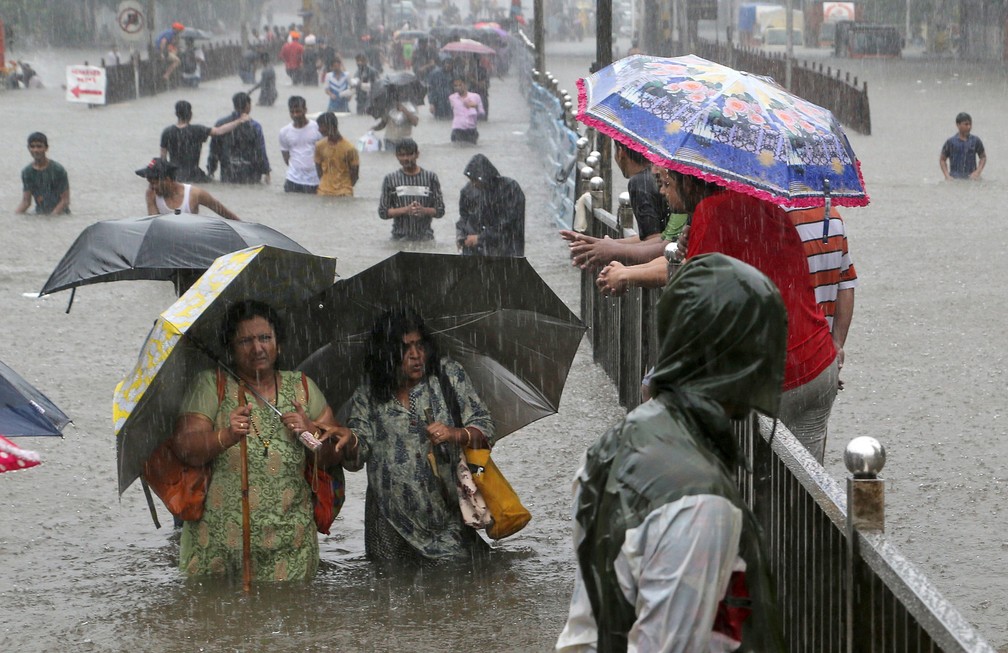 4 de setembro - Pessoas caminham por uma rua inundada após chuvas torrenciais em Mumbai, na Índia. Mais de 1600 pessoas morreram entre junho e outubro na pior temporada de chuvas de monção em 25 anos no país — Foto: Rajanish Kakade/AP