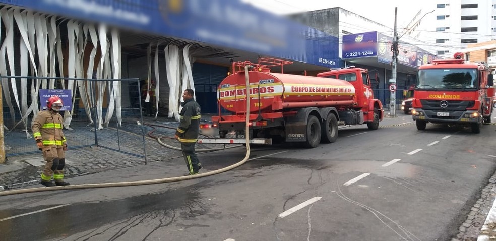 Trabalho dos bombeiros no resfriamento das chamas na manhã desta sexta-feira (9), em loja de descartáveis, em João Pessoa — Foto: Danilo Alves/TV Cabo Branco