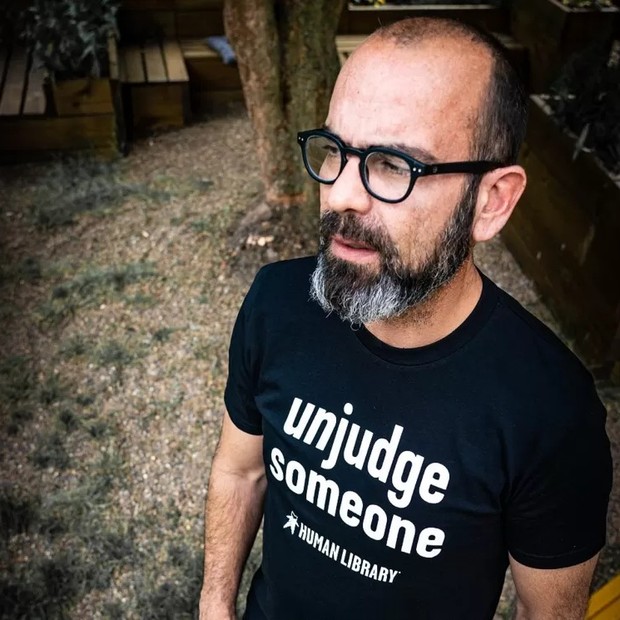 Ronni Abergel, fundador da Biblioteca Humana, com uma camiseta em que se lê "'Desjulgue alguém" (Foto: MENNESKEBIBLIOTEKETS via BBC)