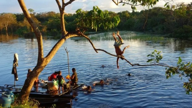 Crianças ribeirinhas brincam no rio enquanto mulheres lavam roupa, em Jutaí (AM) (Foto: MARIA GABRIELA FINK/DIVULGAÇÃO via BBC)