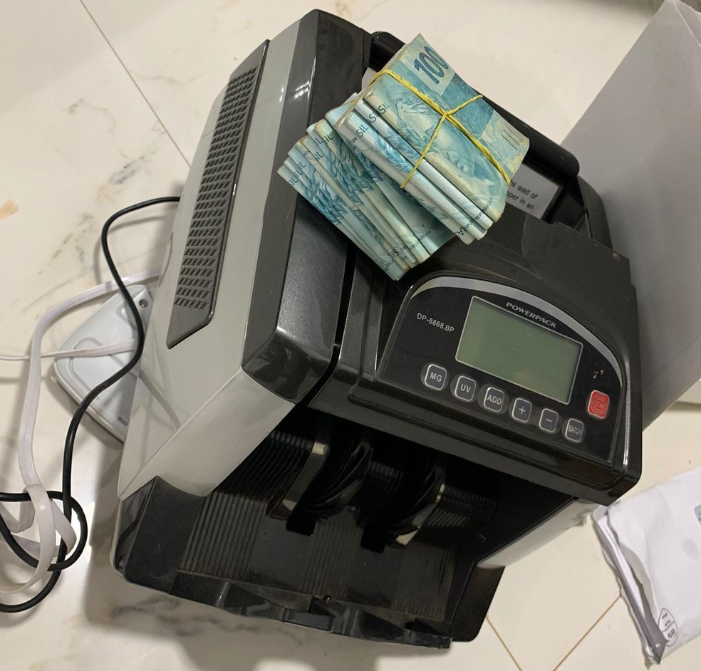 Máquina de contar cédulas e dinheiro apreendidos durante operação, no DF — Foto: PCDF/Divulgação