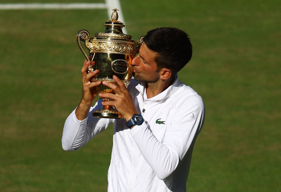 O tenista sérvio Novak Djokovic beija o troféu do Torneio de Wimbledon após derrotar o australiano Nick Kyrgios por 2 sets a 1 — Foto: Hannah Mckay/Reuters