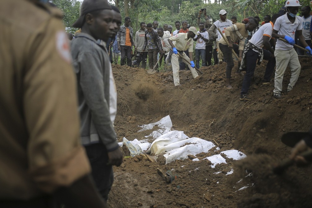 Voluntários da Cruz Vermelha enterram os restos mortais de civis mortos na vila de Mukondi, na província de Kivu do Norte, na República Democrática do Congo, quinta-feira, 9 de março de 2023. — Foto: AP Photo/Socrate Mumbere