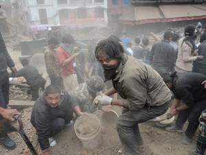 Homem ajuda a limpar o que restou da praça Durbar, patrimônio histórico tomabado pela Unesco, em Katmandu (Foto: Prakash Mathema / AFP)