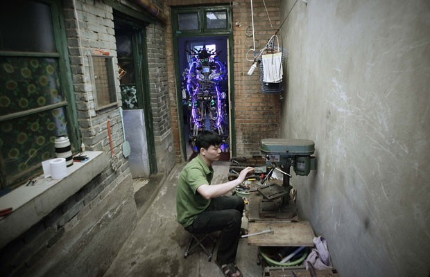 Chinês Tao Xingli, 37, constrói em casa um robô de 2 m de altura com restos de fio e metal (Foto: Suzie Wong/Reuters)