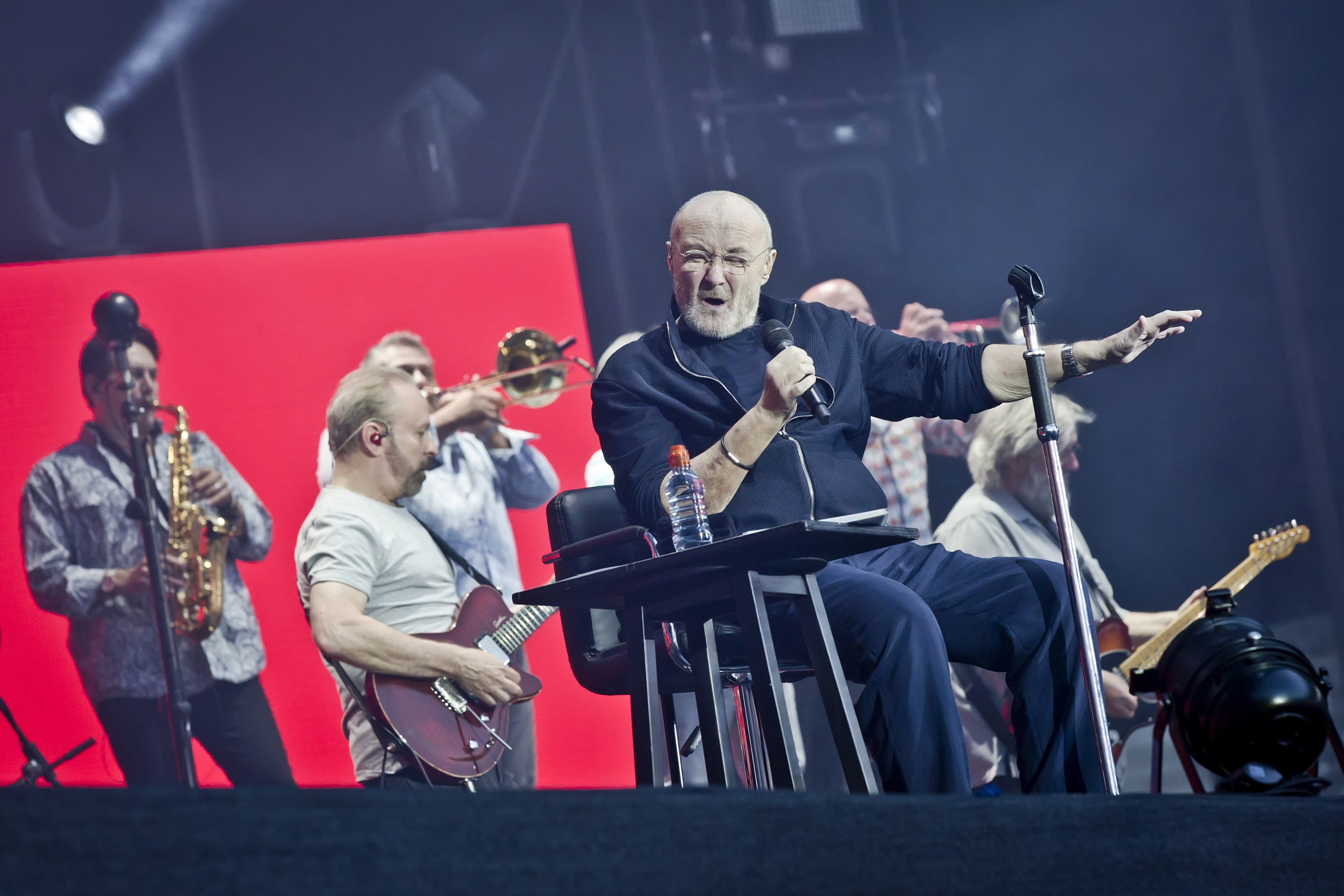 O cantor Phil Collins cantando sentando durante um show recente (Foto: Getty Images)