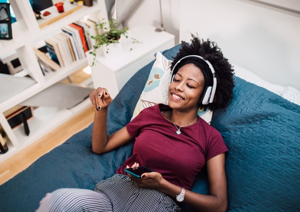 Beautiful African-American woman enjoying in her bed and listening to the music. (Foto: Getty Images)