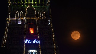 A lua retratada ao ao lado do templo Kapaleeswarar, iluminado por ocasião da celebração de Vaikasi Visagam, em Chennai — Foto: Arun SANKAR / AFP