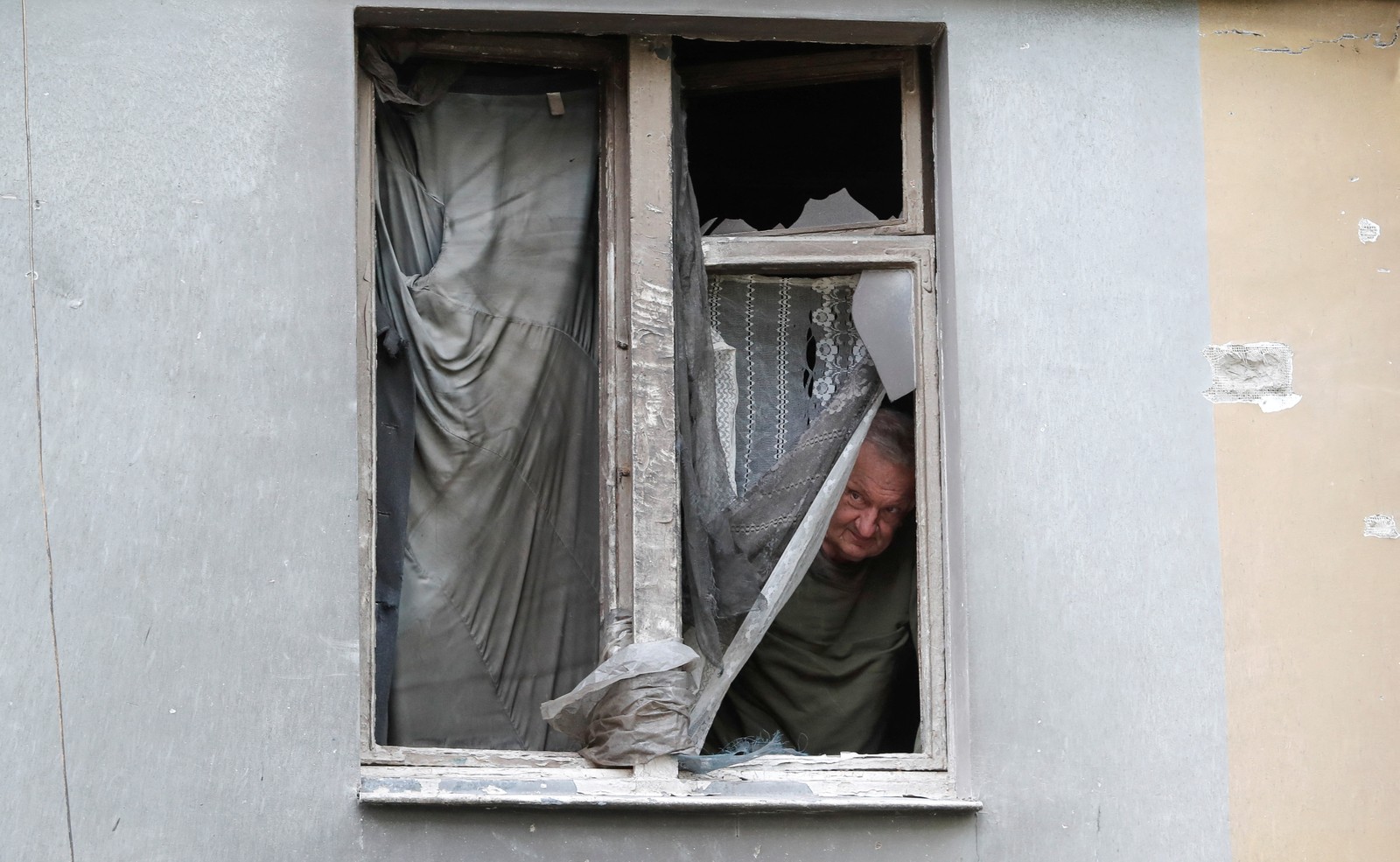 O morador local Vladimir Lebed olha para fora de um apartamento em um prédio danificado durante o conflito Ucrânia-Rússia na cidade portuária do sul de Mariupol — Foto: Alexander/REUTERS