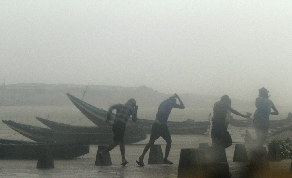 Pescadores deixam praia durante fortes chuvas causadas pelo ciclone Titli, nesta quinta-feira (11) em Ganjam, na Índia — Foto: AP Photo