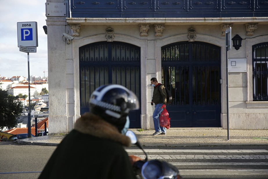 Um homem com máscara para se proteger da covid-19 caminha por uma rua de Lisboa, Portugal