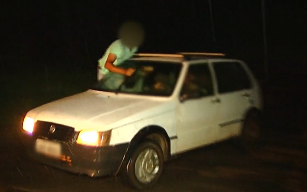 Passageiro sentado na janela de carro para mover limpador de para-brisa durante chuva em Luziânia, Goiás — Foto: Reprodução/TV Anhanguera