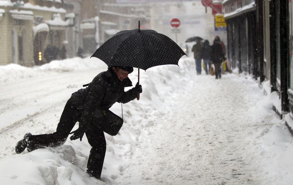 Mulher anda com dificuldade na neve no centro de Zagreb, Croácia. (Foto: Darko Bandic/AP)