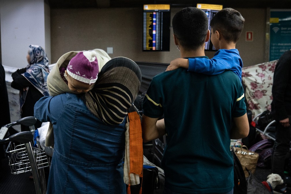 Jornalista afegão com sua mulher e filhos na chegada ao Brasil  — Foto: Fábio Tito/g1