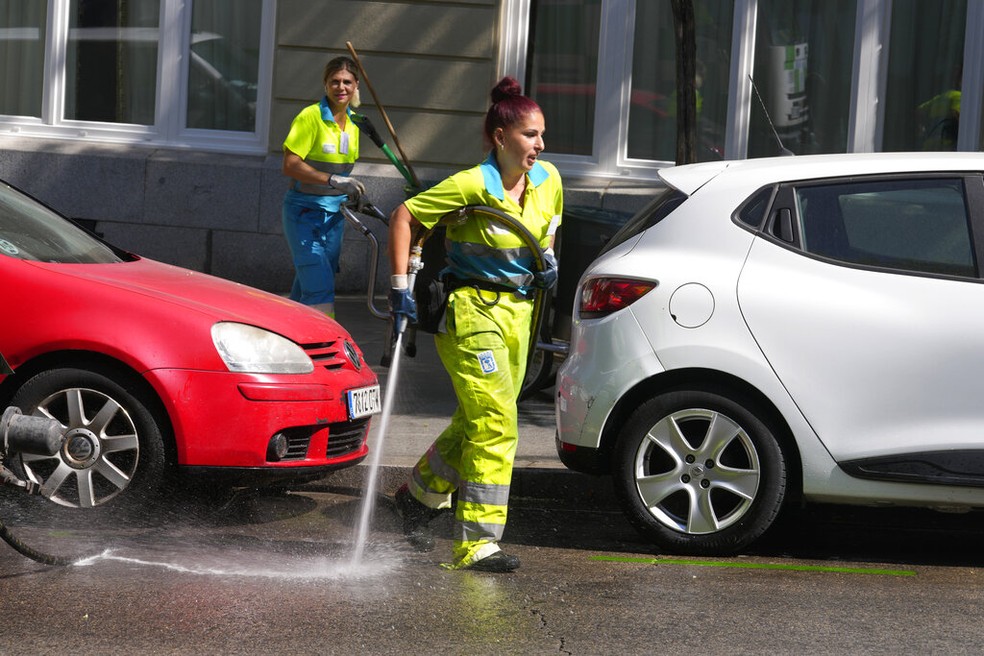Funcion&aacute;ria do servi&ccedil;o de limpeza urbana de Madri, na Espanha, lava ruas da cidade para refrescar asfalto, em 19 de julho de 2022. &mdash; Foto: AP