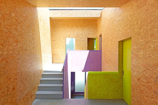 Em contraste com o piso de concreto, grandes placas de OSB foram tingidas de amarelo fluorescente e roxo, cores também aplicadas nos armários e portas. Na escada, a luminosidade da soleira ajuda a destacar as nuances ousadas (Foto: Thomas Jantscher e Nicolas Sedlatchek / Divulgação)