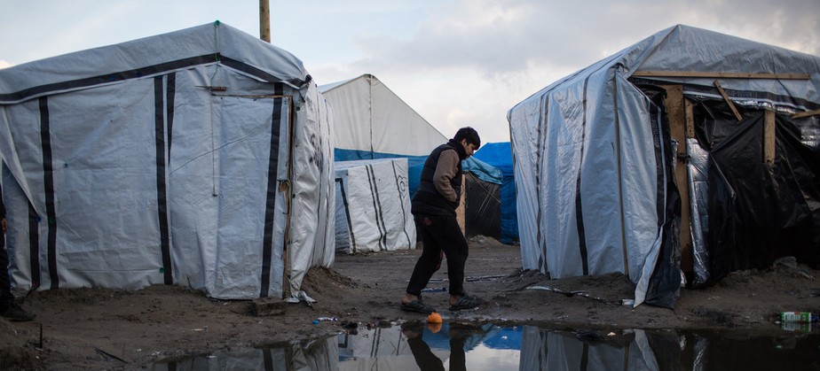 Menino caminha por um acampamento de migrantes em Calais, norte da França. De acordo com as estimativas, cerca de 900 migrantes e requerentes de asilo estão abrigados na área, muitos sem banheiros ou lavatórios