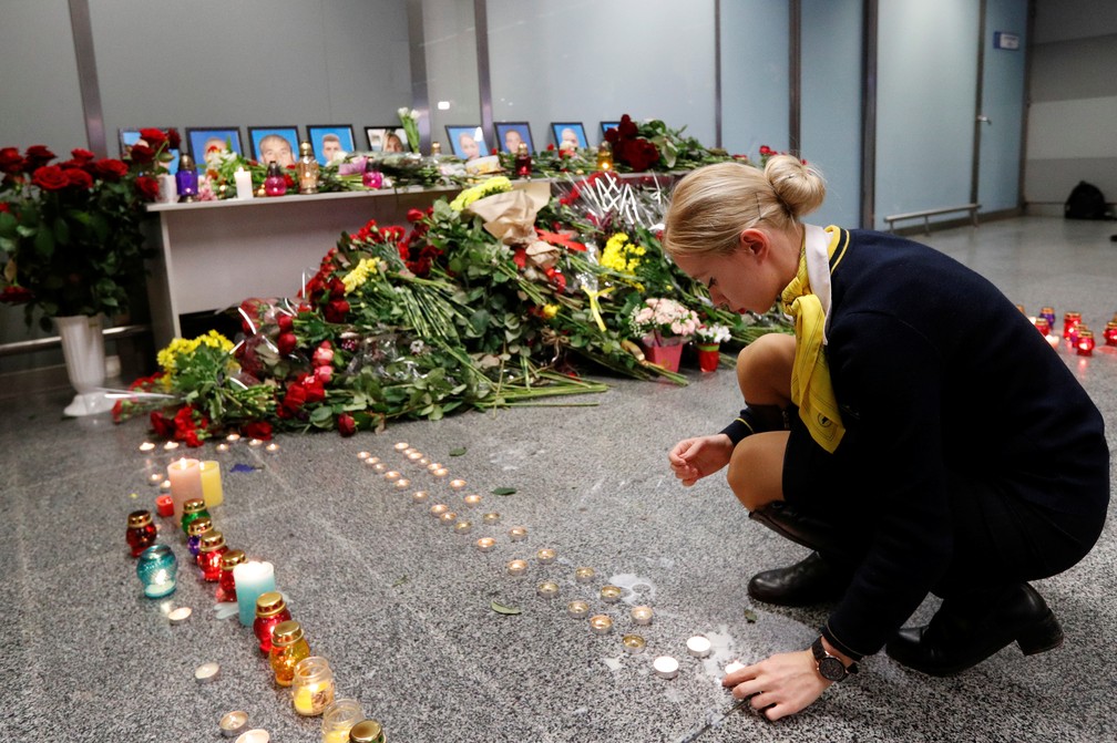 Uma colega dos tripulantes que estavam a bordo do avião que caiu em Teerã coloca uma vela no memorial no aeroporto de Kiev, na Ucrânia, nesta quarta (8). — Foto: Valentyn Ogirenko/Reuters