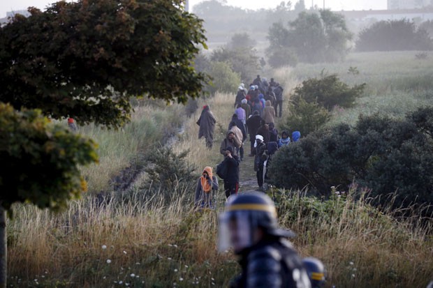 Imigrantes que estavam bloqueando o acesso de caminhões ao Eurotúnel são dispersados por policiais perto de Calais, na França, neste domingo (2) (Foto: Pascal Rossignol/Reuters)
